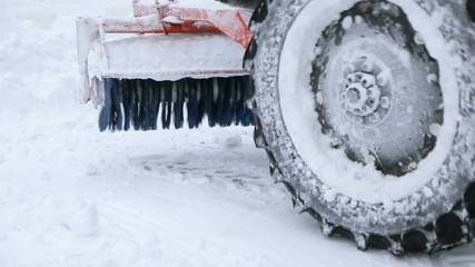 Specialized snow plow with large plow and brushes remove snow from the town square. Snow plow clears street after heavy snowfall in January.
