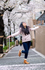 Obraz na płótnie Canvas An asian woman enjoy seeing cherry blossom in full bloom in Tokyo, Japan and trowing cherry blossom petals in the air.