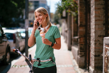 Fototapeta premium Beautiful girl talking on phone holding ice cream