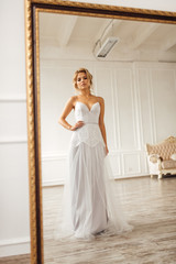 Fototapeta premium the bride in a beautiful dress looks in the mirror