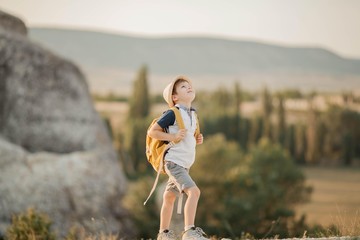 A beautiful little boy is standing in the mountains. Tourism. Campaign. Fall.