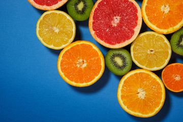 Assortment of various cut raw fruits on blue background, copy space