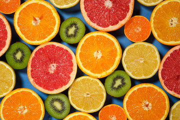 Assortment of various cut raw fruits on blue background, full frame