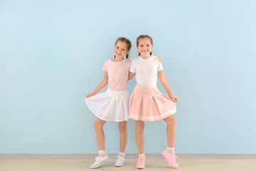 Portrait of cute twin girls near color wall