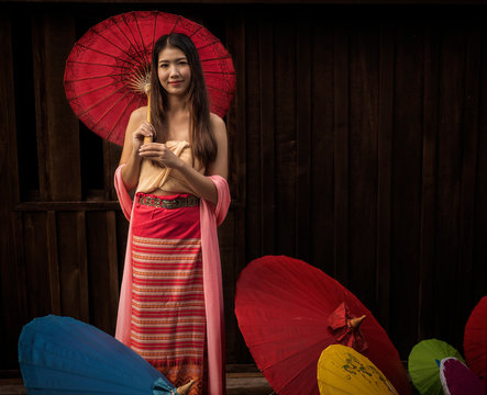 Portrait of happy young Asian woman holding red umbrella with copy space for Ad. text or product your. Cute cambodian girls. beauty ,Fashion concept