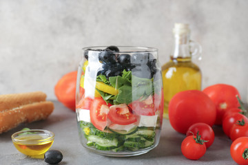 Fototapeta na wymiar Glass with tasty Greek salad on grey table