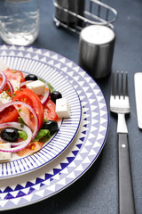 Plate with tasty Greek salad on table