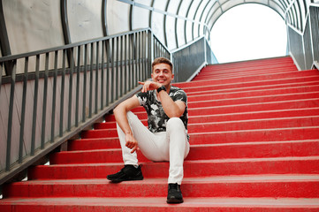 Lifestyle portrait of handsome man posing in red stairs of the city tonnel.