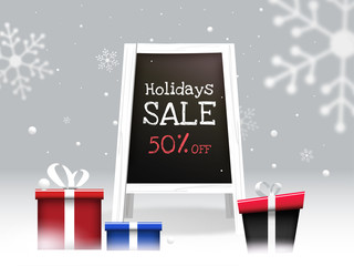 Holiday Sale text in painting board with 50% discount offer and gift boxes on winter snow background. Can be used as banner or poster design.
