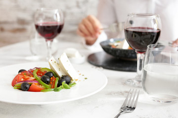 Plate with tasty Greek salad on table