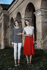 Obraz na płótnie Canvas Outdoor fashion portrait of two young beautiful women wearing fashionable clothes posing on the street