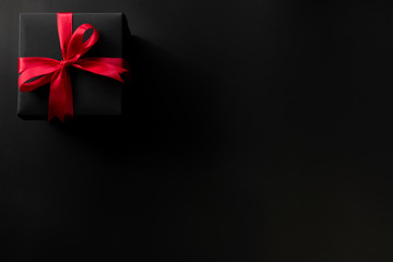 Top view of black christmas gift boxes with red ribbon on black background with copy space for text., black friday advertisement. - obrazy, fototapety, plakaty