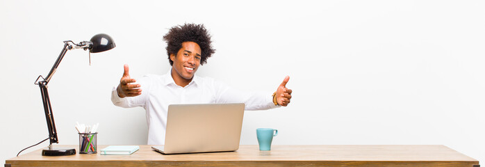 young black businessman smiling cheerfully giving a warm, friendly, loving welcome hug, feeling...