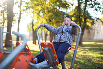 Kid boy does workout on trainer equipment outdoor. Children, sport, activity and healthcare concept