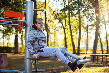 Smart kid boy does workout on trainer equipment outdoor. Children, sport, activity and healthcare concept