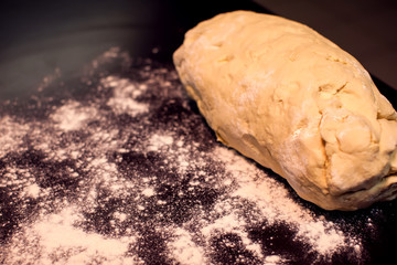 A dough with flour on the black background. Homemade food concept