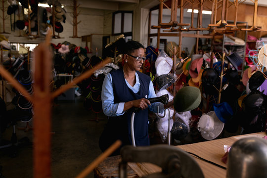 Woman holding a hat in a hat factory
