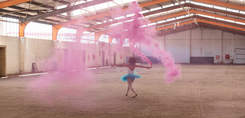 Female dancer in an empty warehouse holding smoke grenade