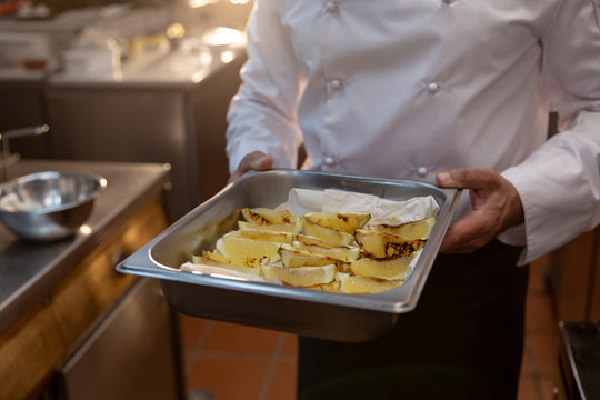 Chef holding a metal tray in kitchen