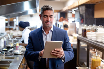 Restaurant manager using a tablet in a kitchen