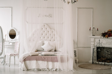 White bedroom interior with nobody. large cozy bed with a white canopy and oval dressing mirror...