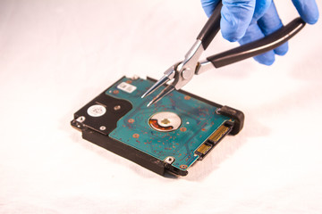 fixing a hard disk drive with one hand with gloves and a special tweezers