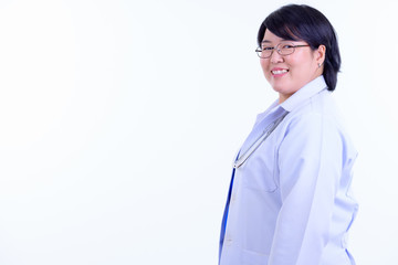Profile view of happy overweight Asian woman doctor looking at camera