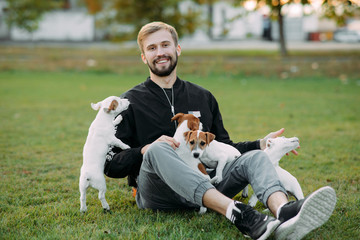 Young man plays with Jack Russell puppies.