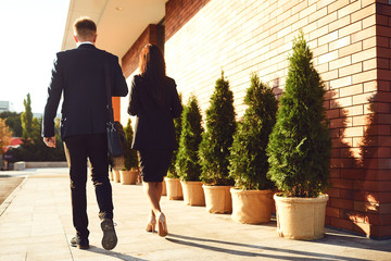 Back view. Business People walk along the city street.