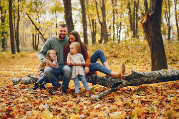 Fototapeta premium Family in a autumn park. Woman in a red sweater. Cute childrens with parents