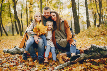 Family in a autumn park. Woman in a red sweater. Cute childrens with parents