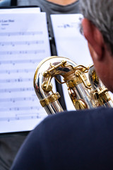 Obraz premium Cropped image of a back turned saxophone player. In the background, an out of focus score