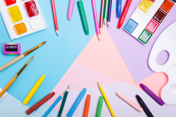 View from above, crayons, colour pencils, watercolor on the colorful peaces of paper.Empty space in the middle for design