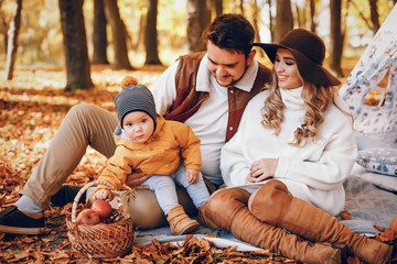 Family have fun in a autumn park. Cute blode in a white sweater. Parents with little son. Family sitting near wigwam  © prostooleh