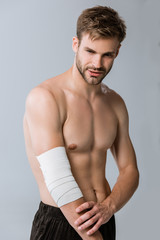 Fototapeta na wymiar shirtless sportsman with elastic bandage on elbow isolated on grey
