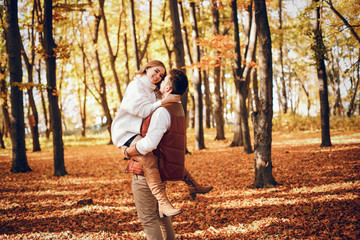 Fototapeta premium Couple have fun in a autumn park. Cute blode in a white sweater.