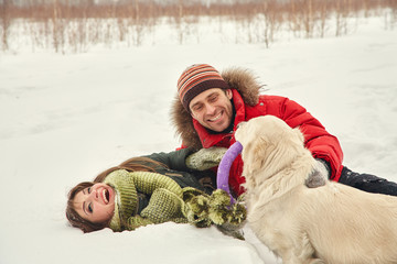 couple with a dog on a winter walk. man and woman with labrador outdoors