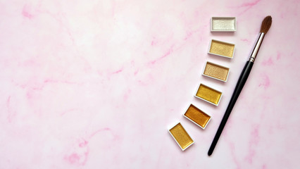 Paint brush and golden color palettes, with pink background.