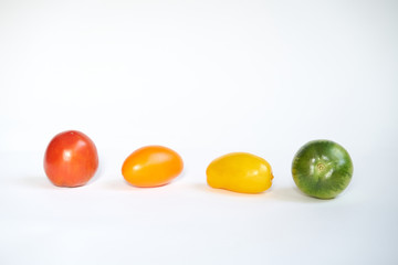 Red, green and yellow tomatoes in line on white background