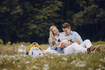 beautiful long-haired blonde with her handsome man and small newborn sitting son in the park