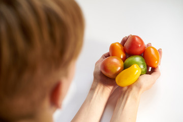 woman holding multicolored tomatoes on white background