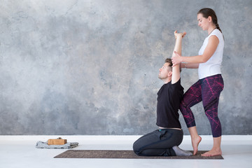 Yoga instructor helping her student to stretch muscles.