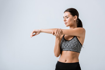 attractive sportswoman with arm pain isolated on grey