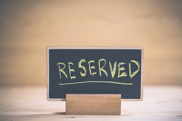reserved text on wooden blackboard on wooden table.