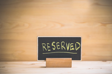 reserved text on wooden blackboard on wooden table.