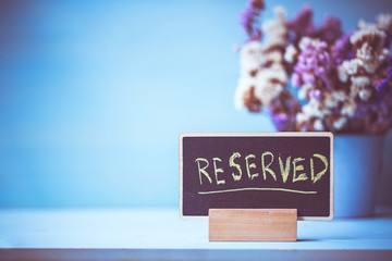 reserved text on wooden blackboard on table over blue wall background.