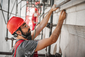 Man worker standing on scaffolding and restore old building facade