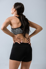 back view of sportswoman with lower back pain isolated on grey