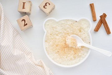 Rice porridge with cinnamon in funny bear shape plate, healthy breakfast for kids.