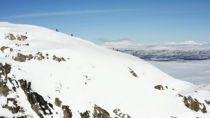 Unidentified people walking to the mountain top, sunny winter day in Northern Sweden. Breathtaking view over Scandinavian Mountains